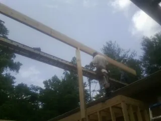 Carpenter setting a ridge beam over a new addition frame — Ice Dam Removal by Roofing Brothers in Saint Johnsbury