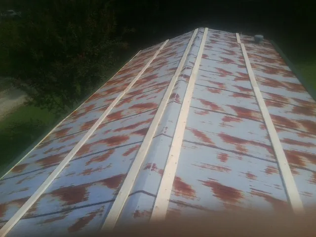 Rusted metal roof panels with new wood purlins before replacement — Storm Damage Roof Repair in Saint Johnsbury by Roofing Brothers