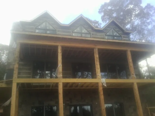 Dormers and porch framing on a large log home under construction — Roof Coating work by our crew in Saint Johnsbury