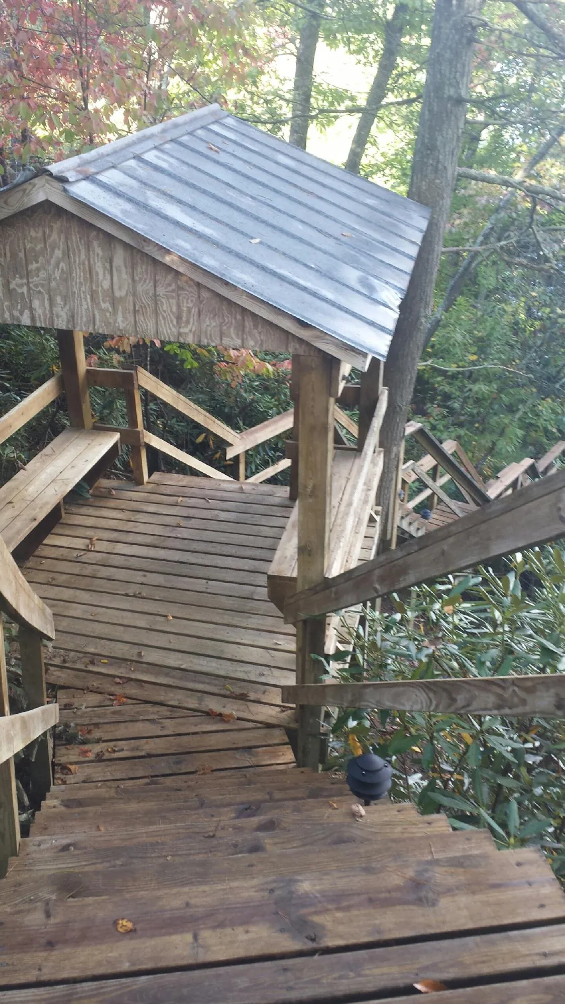 Metal roofed shelter over wooden steps on a wooded walkway — Skylight Repair & Installation work by our crew in Saint Johnsbury
