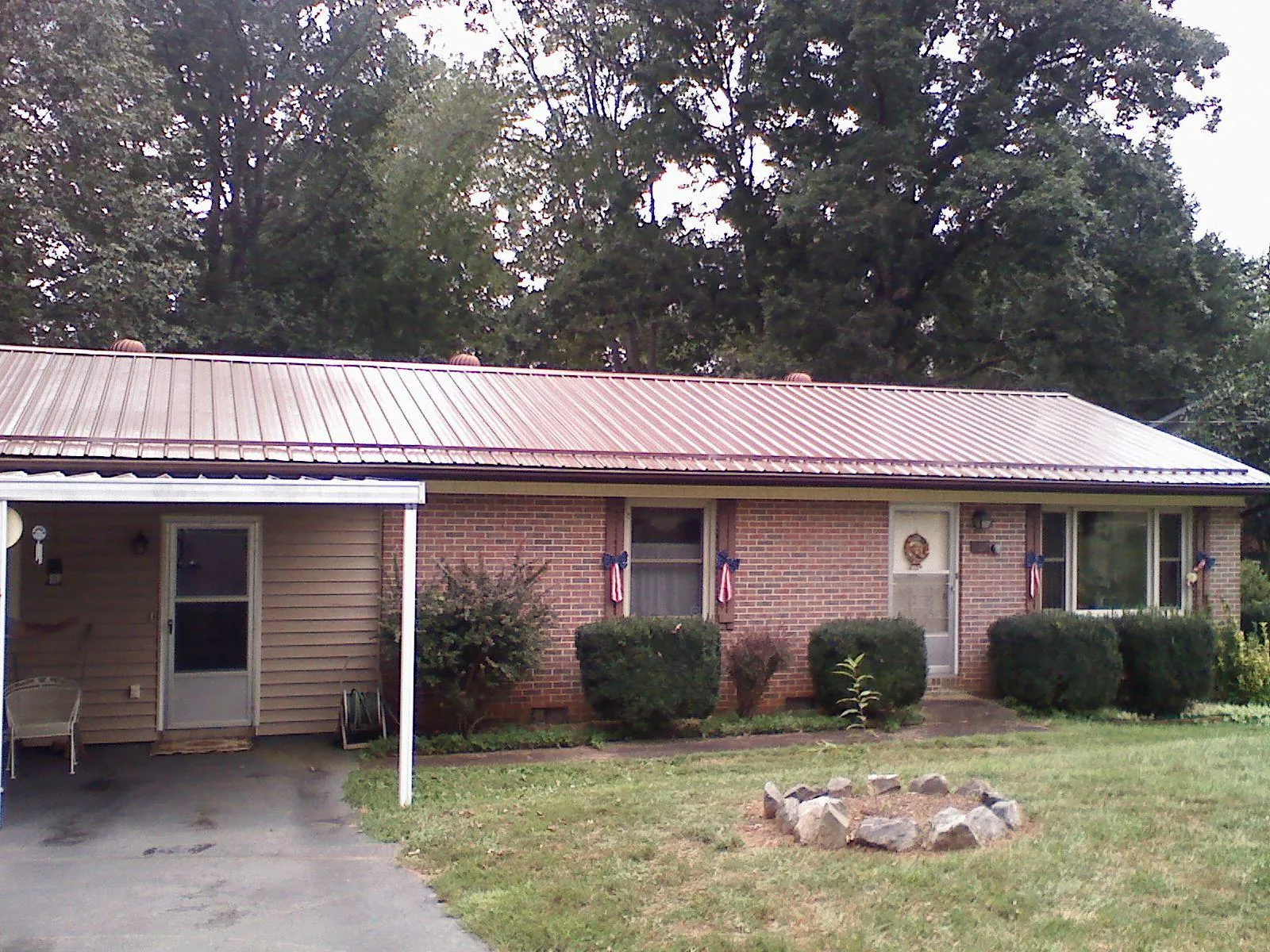 Bronze metal roof and carport on a brick ranch home — Roof Repair work by our crew in Saint Johnsbury