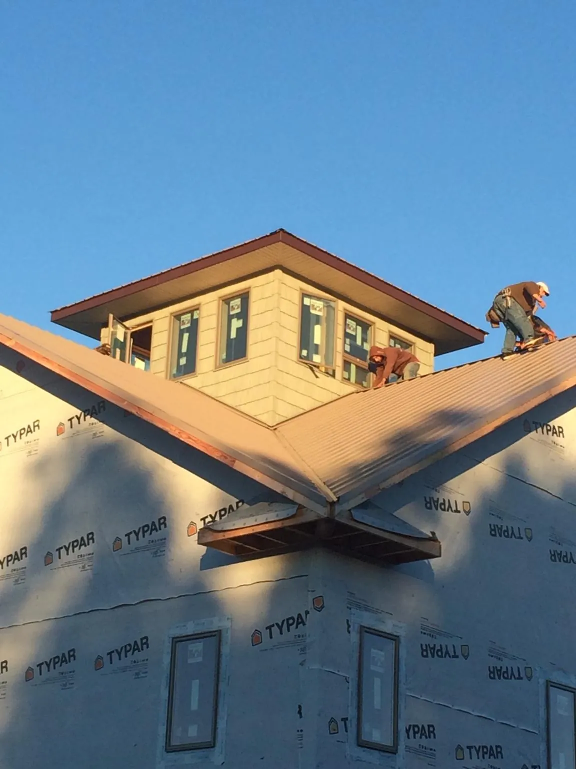 Roofers working around a rooftop cupola on a new metal roof at sunset — Roof Waterproofing in Saint Johnsbury by Roofing Brothers